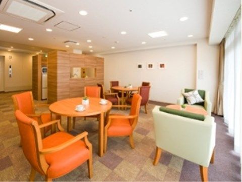 カーペット敷きの床面、一面が大きな窓になっており、明るい。応接セットがあり、入居者様の交流の場として、ティータイムなどを楽しむこともできる。