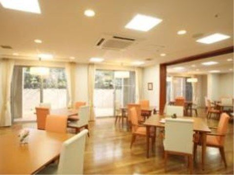 明るいフローリングの床であり、広々とした空間になっている。テーブルに配置された椅子は、オレンジと白の２色である。