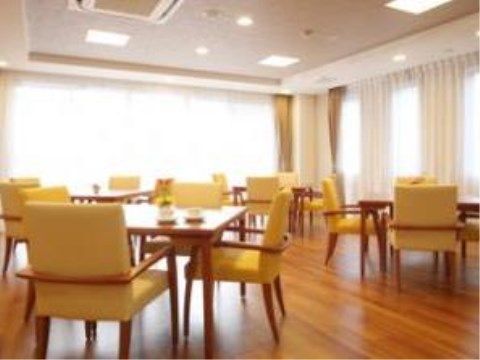 黄色いおしゃれな椅子が並べられたダイニングルーム。テーブル間の間隔が広くなっており、窓が大きいため開放的になっている。