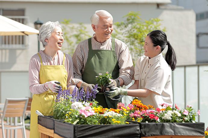 りんごを見ながら楽しそうにスケッチをするご入居者様と見守るスタッフ