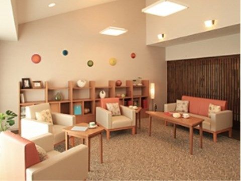 天井が傾斜した明るい室内に、ソファ１台と一人掛けの椅子３脚がゆったり置かれている。白い壁にカラフルな丸い飾りがある。