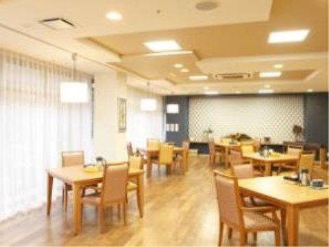 毎日の食事が提供される共有スペースは窓が大きくとても明るい。木製のテーブルセットが多数並べられている。