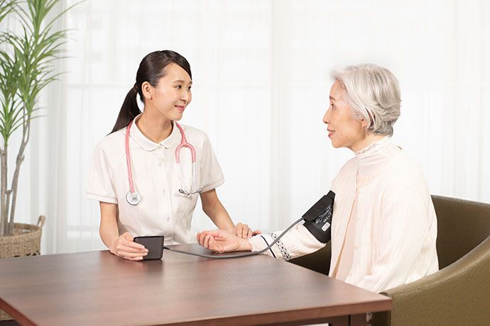 廊下を車椅子で押してもらいながら居室へ向かうご入居者様と職員
