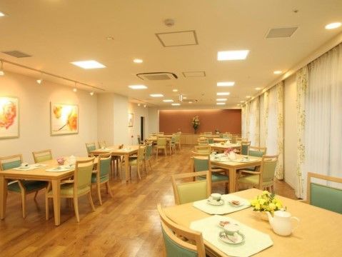 広々とした落ち着いた雰囲気のダイニングである。窓が大きく、光が差し込む空間である。テーブルの上にはかわいらしい花を飾っている。