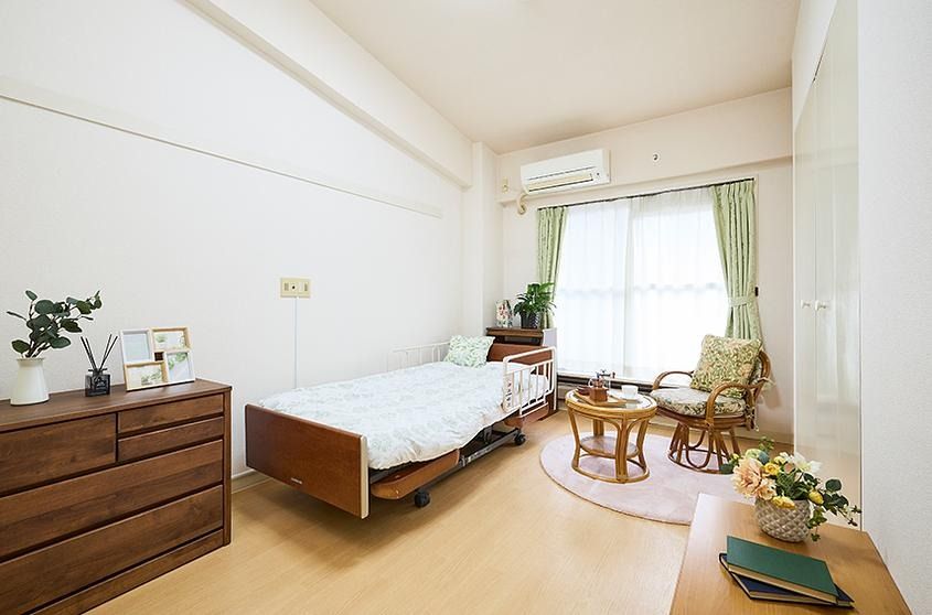 ベッドや電気スタンド、鏡台、コーヒーテーブルと椅子、テレビ台などの置かれた部屋である。居心地よく整えられている。