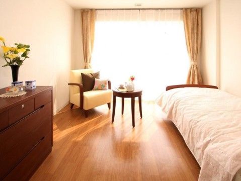 壁全面が掃き出し窓でとても明るい。壁際にベッドが置かれているが、家具を置いても十分な広さがあり、カフェテーブルとソファなどが置かれている。