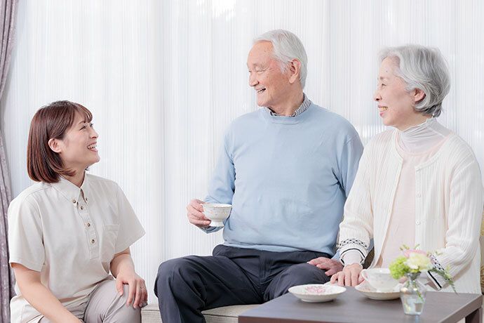 ソファーに座られている、ご夫婦で入居されている方へお声がけをする職員