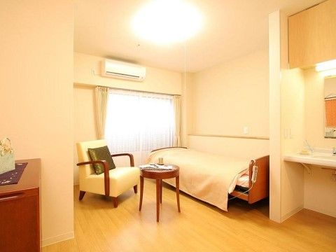 リモコンで操作可能な介護用ベッドや椅子、テーブルなどが置かれている居室。車椅子に座ったまま使用できる洗面台が備え付けられている。