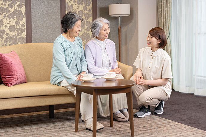 ひざまずいている女性スタッフと談笑する男女の入居者様たち