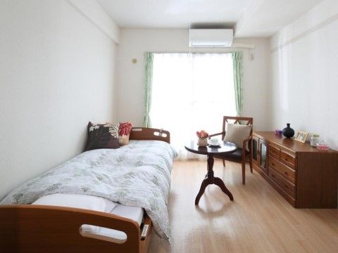窓には緑色のカーテンがかかっている。カーテン上にエアコンが設置してあり、室温が調節できる。フローリングの床である。