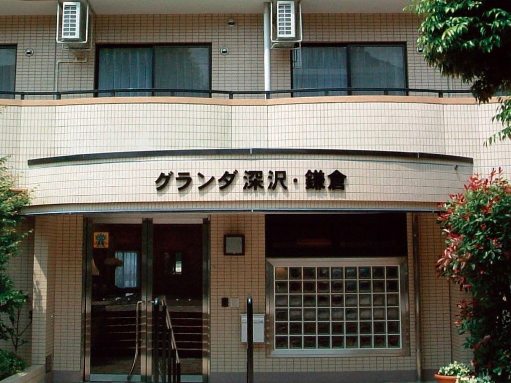 屋根の前に、黒い文字プレートで施設名がはっきりと記してある。ドアには銀の縁があり、横向きに何本かの棒が入っている。