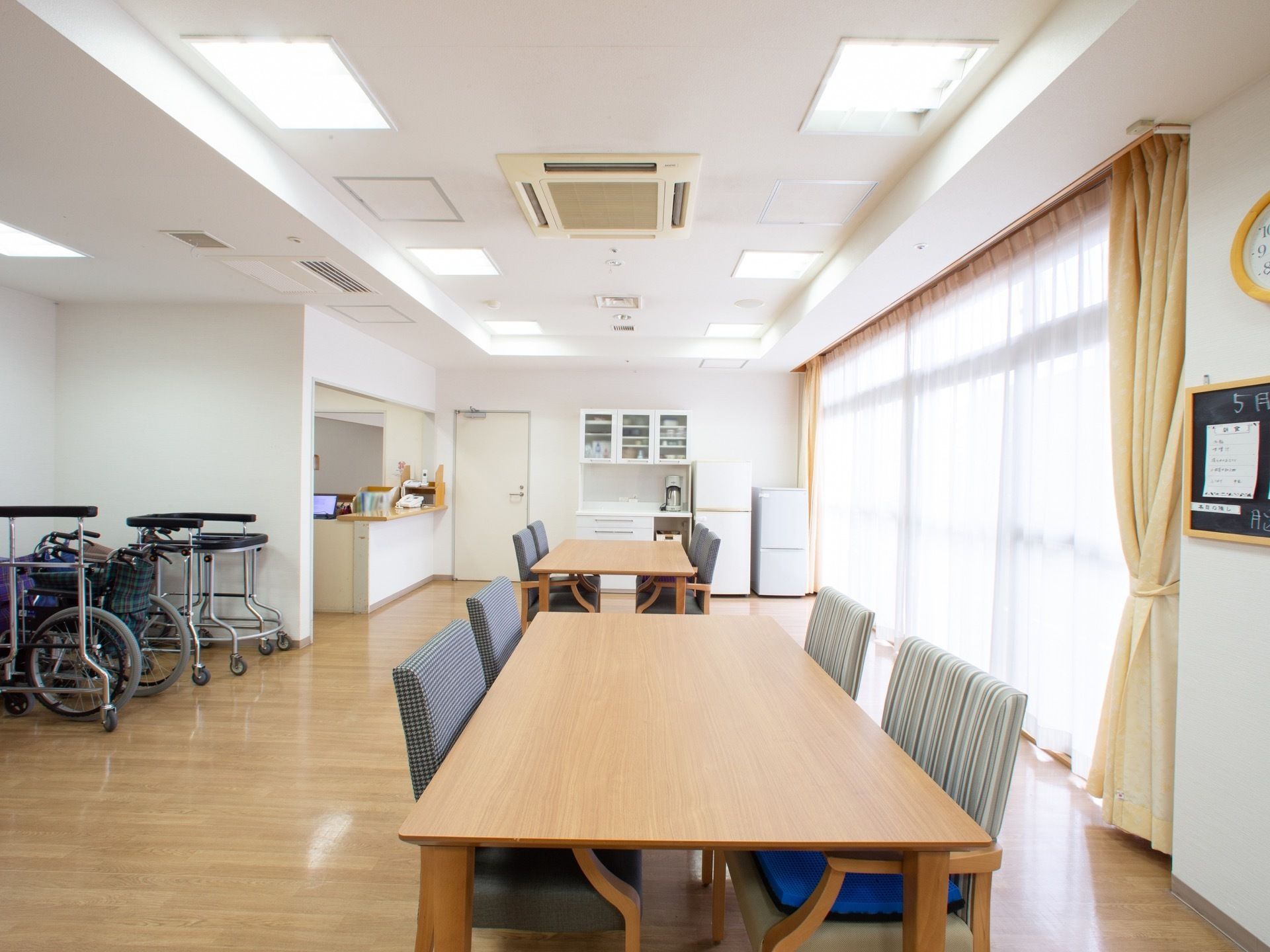 長テーブルと椅子のセットが二つ配置された明るい広い部屋