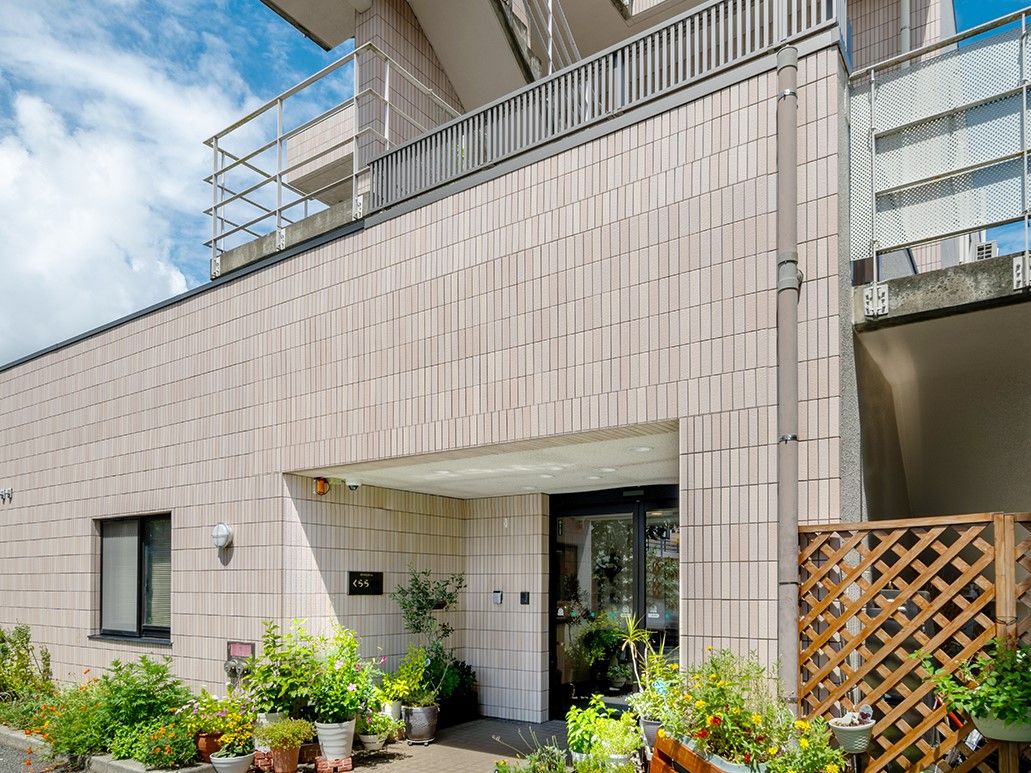 ３階建ての建物がある。入口は段差がなく、出入りしやすい自動ドアになっている。手前には数台分の駐車場がある。