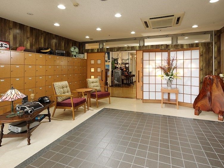 白い壁が清潔感のある部屋に介護用のベッドが配置されている。大きな掃き出し窓があり、その上にエアコンが設置されている。