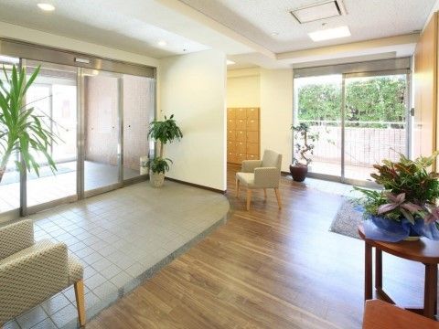 エントランスはバリアフリー構造になっている。玄関部分はグレーのタイル張りで、室内の床は木調である。ソファや観葉植物が設置されている。