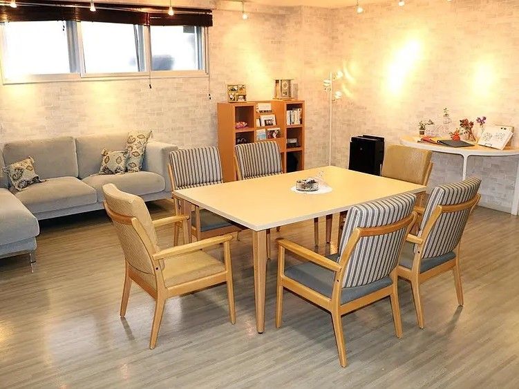 介護ベッドや大型のタンス、テレビ台などが置かれている。大きな窓があり、窓の上にエアコンが備わっている。