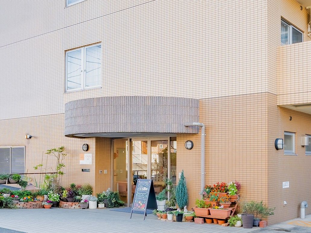 ４階建ての建物で、明るいオレンジ系の茶色のツートンカラーの外壁である。入口の左右に、駐車スペースが設けられている。