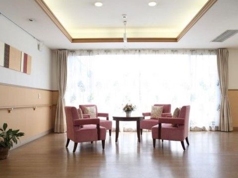 大きな窓から日差しが差し込み、開放感のあるエントランス。ピンクの椅子、テーブルが設置されており、ゆったりと談笑を楽しむことができる。