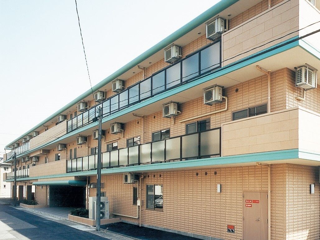 オレンジを基調とした明るい雰囲気の施設。三階建ての大きな建物である。各居室にベランダが設置されている。