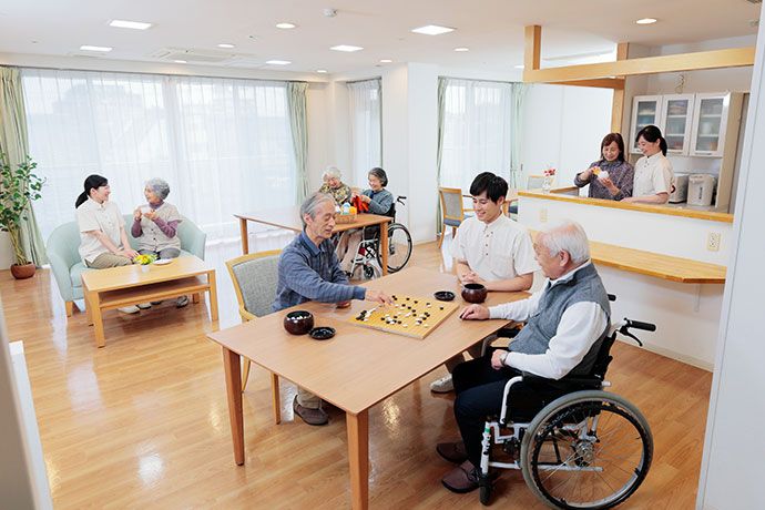 女性スタッフのサポートで、にこやかな表情で薬を飲もうとしている女性入居者様