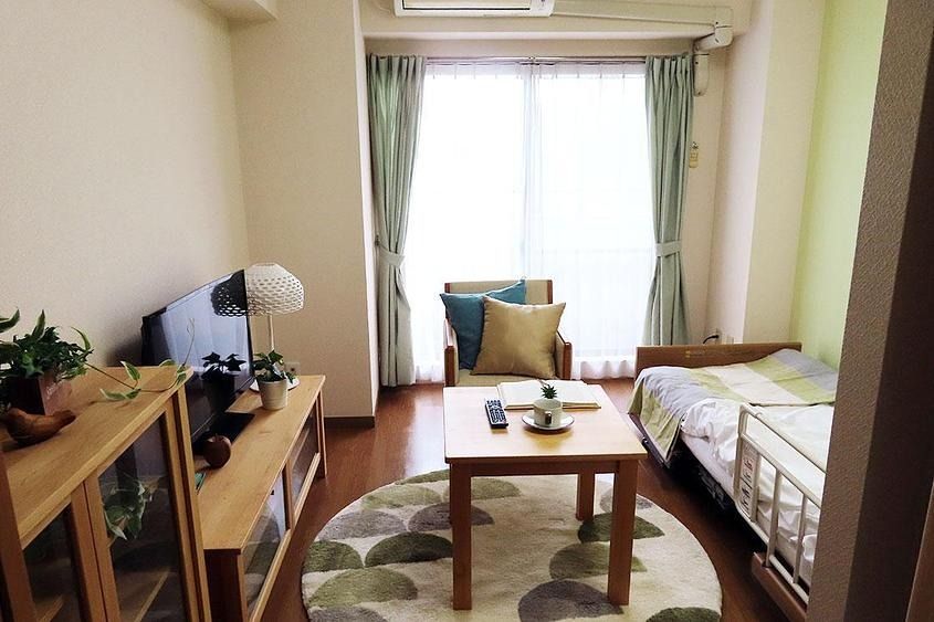 木目調のフローリング部屋である。掃き出し窓を設置し、採光を考慮した設計。窓側にクッションつきの椅子とテーブルが置かれてある。