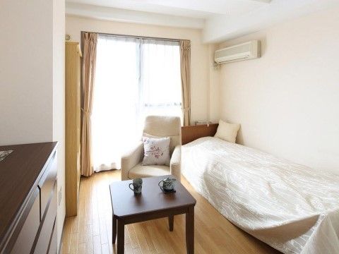 窓があり外からの光が差し込む明るい部屋。エアコンが完備されている。ベッド、テーブル、ソファがあり、寛ぐことができる。
