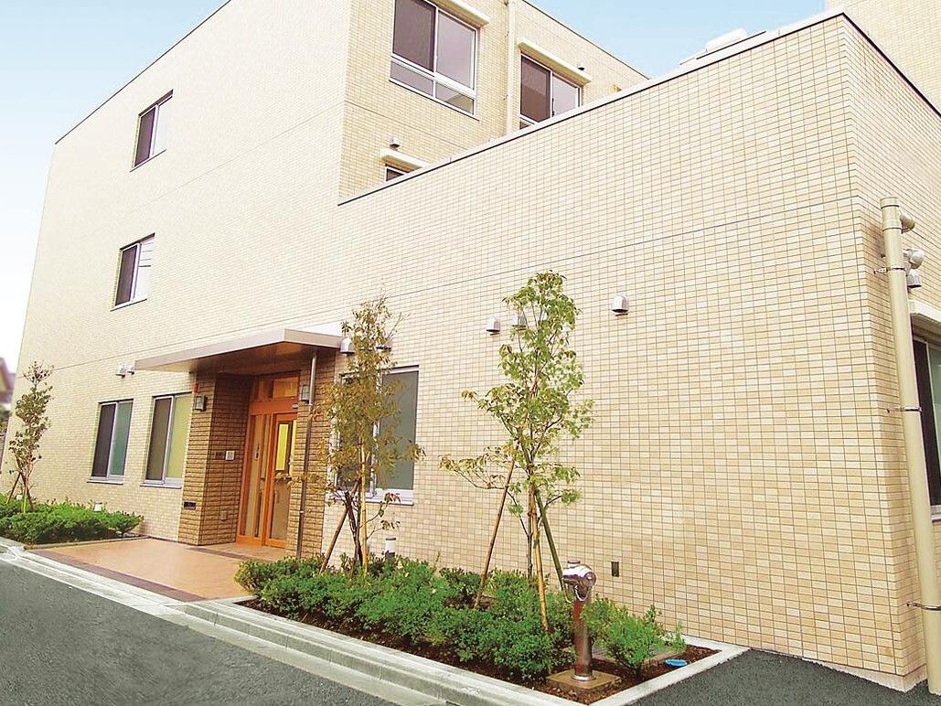 落ち着いたオレンジ色で縁取られた自動ドアがあり、脇にプランターが置かれている入口