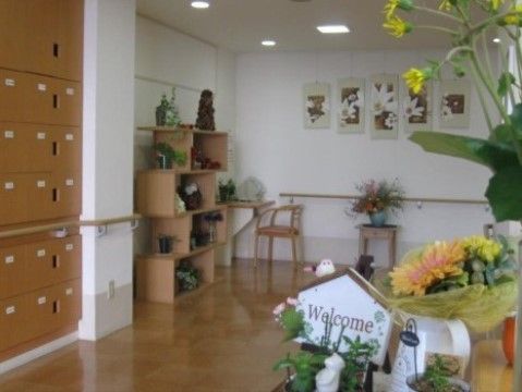 白い壁に木のフローリングのエントランスである。ロッカーがあり、そこには手すりも付いているため、靴を取り出す際も便利である。