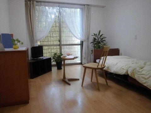 居室はゆとりのある設計になっている。棚の上にテレビが設置されており、テーブルには本やライトが置かれている。