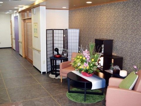 グレーのタイル張りのエントランスには、和の趣のあるつい立てや飾り棚、テーブルが置かれている。ピンク色の一人掛けソファが二台ある。