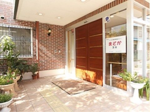 レンガ調のあたたかい雰囲気がただようエントランスである。まわりにたくさんの花木を飾り、緑を取り入れている。