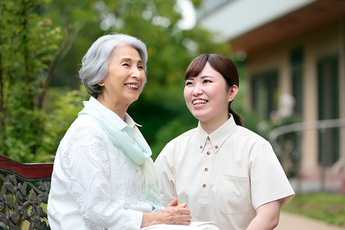 椅子に座る年配の女性よりも目線を低くして話す女性スタッフ