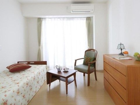 突き当りに窓がある明るい室内には、窓上にエアコンがついている。低床型ベッドがあり、反対側の壁に衣装ダンスが置いてある。