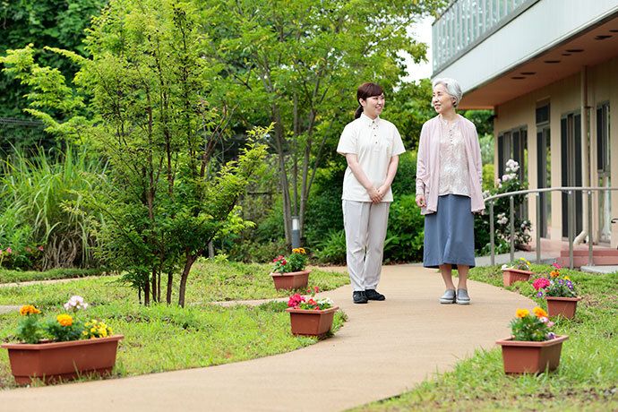 天候の良い日の屋外で、笑顔で話す車椅子の男性とベンチに座った女性