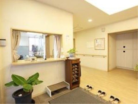 玄関の上り口の横側に受付窓口があり、下部の隅に観葉植物を飾っている。木製の小さめのスリッパの収納棚を置いている。