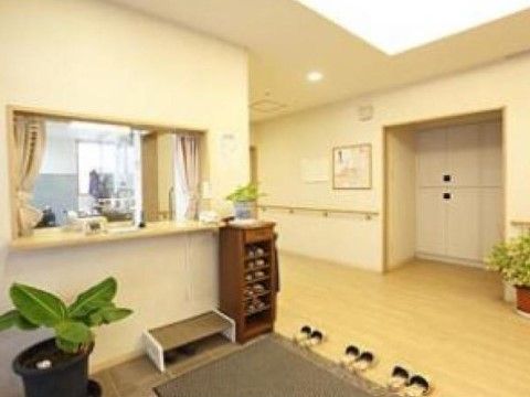 玄関ドアから左側に、スタッフが常駐する大きな受付窓口を設けている。上り口にスリッパを間隔を置いて並べている。