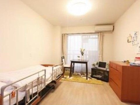 大きなガラス戸際に、一人掛けのテーブルを置いている。傍にテレビを備え、壁際に介護用ベッドを配置している。
