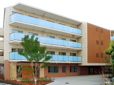 白と茶を基調とした４階建ての施設の外観。敷地内はバリアフリーに配慮されており、車椅子をご利用の方にもスムーズに移動していただける。