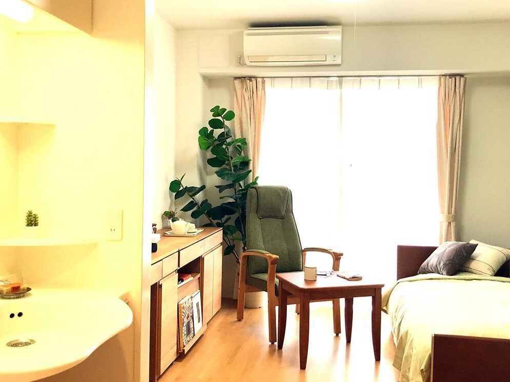 白を基調とした空間に、フローリングのライトベージュとカーテンや観葉植物の緑がアクセントとなっている。