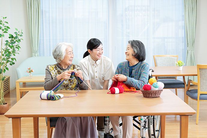 ベッドから車椅子への移動をサポートするために身をかがめている男性スタッフ