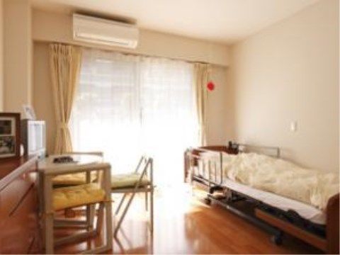 壁側にタンスがあり、タンスに付けるようにしてテーブルが置いてある。椅子の上には黄色のクッションが敷いてある。