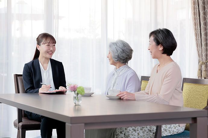 テーブルの席に腰かける２名の女性と１名の男性が向かい合い談話している光景
