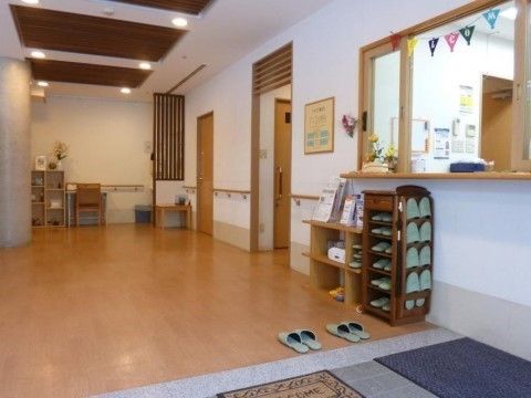 エントランスには引き戸の小窓がついた受付が設置されている。花が飾られ、スリッパラックが置かれた温かみのある空間である。