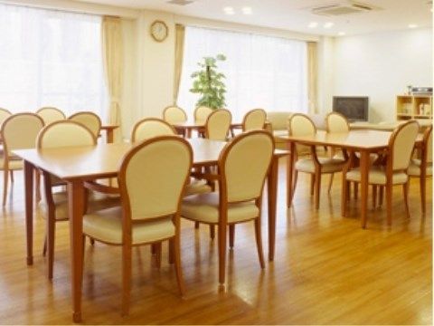正面に掃き出し窓が２面ある明るい室内には、４脚ずつ椅子が並んだダイニングセットが５つ、間を空けて置かれている。