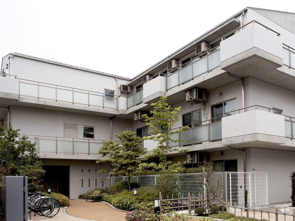 鉄筋3階建ての施設の外観。施設前には庭が作られ、エントランスは緩やかなスロープになっている。駐車場も複数台分が完備されている。