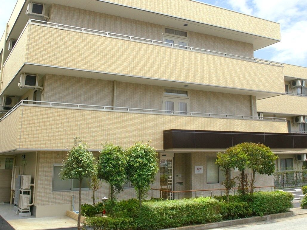 施設前には駐車場がある。玄関までの通路は車椅子でも通りやすいよう広めにとられ、手すりも取り付けられている。