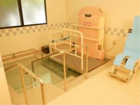大浴場は浴槽周りに手すりを多く設置し、１人で入る練習をすることもできる。浴室用の車椅子が置かれている。