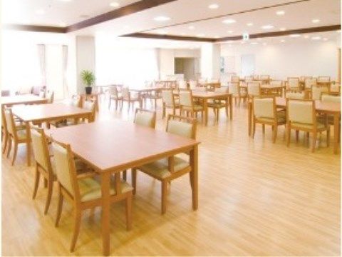 広い間隔で4人掛けのテーブルが並べられている。室内は窓からの採光により明るくなっている。観葉植物が置かれている。