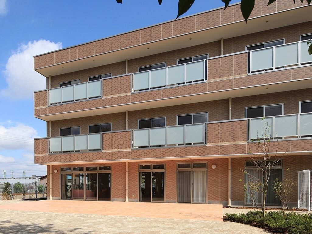 ベージュの壁をしたマンションのような外観をしている。ベランダがついており、１階部分の窓は大きく開放的。