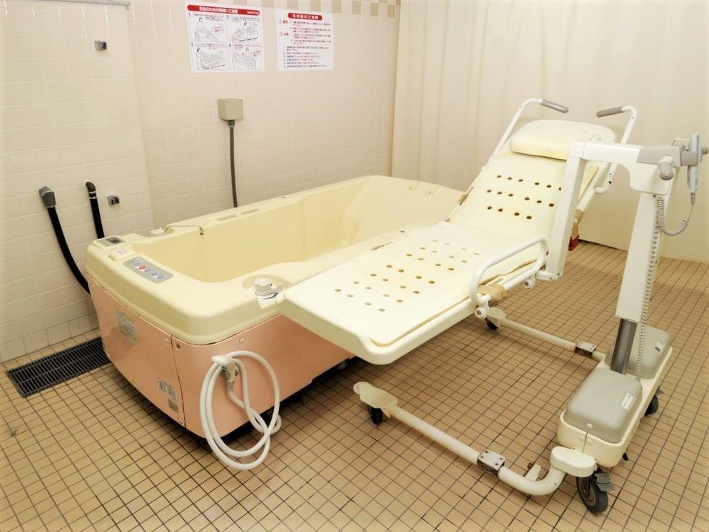 寝たままの状態で入浴できるストレッチャーと浴槽が設置された浴室